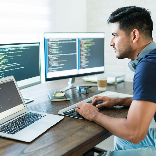 Software developer working at multiple screens